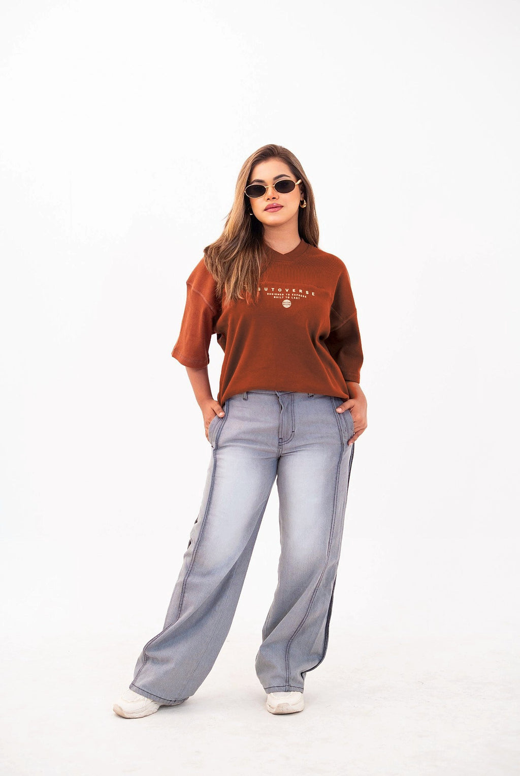 Sutoverse brown oversized drop tee, full length with grey jeans and sunglasses