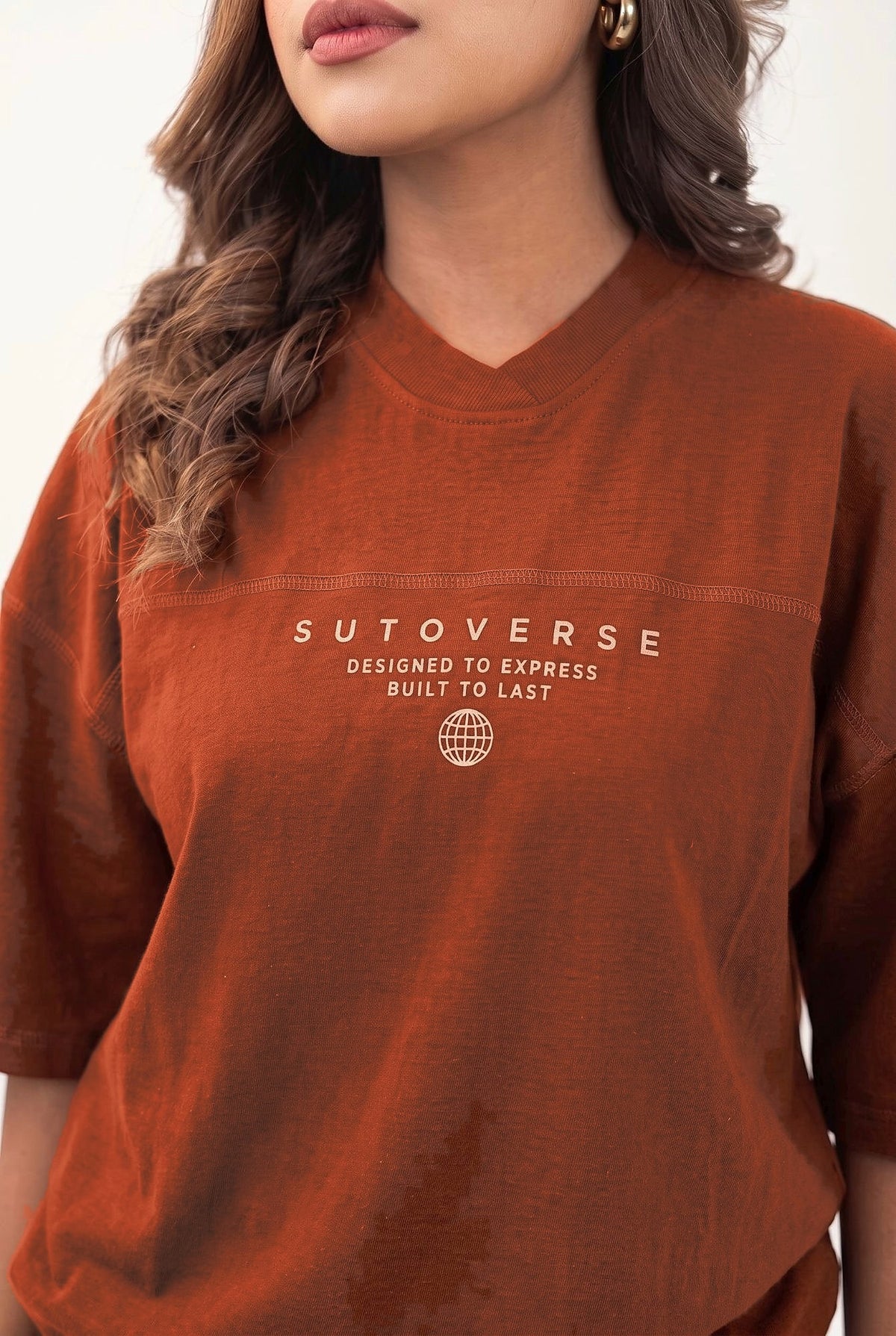 Close-up of the V-neck collar and Sutoverse chest print on the brown tee