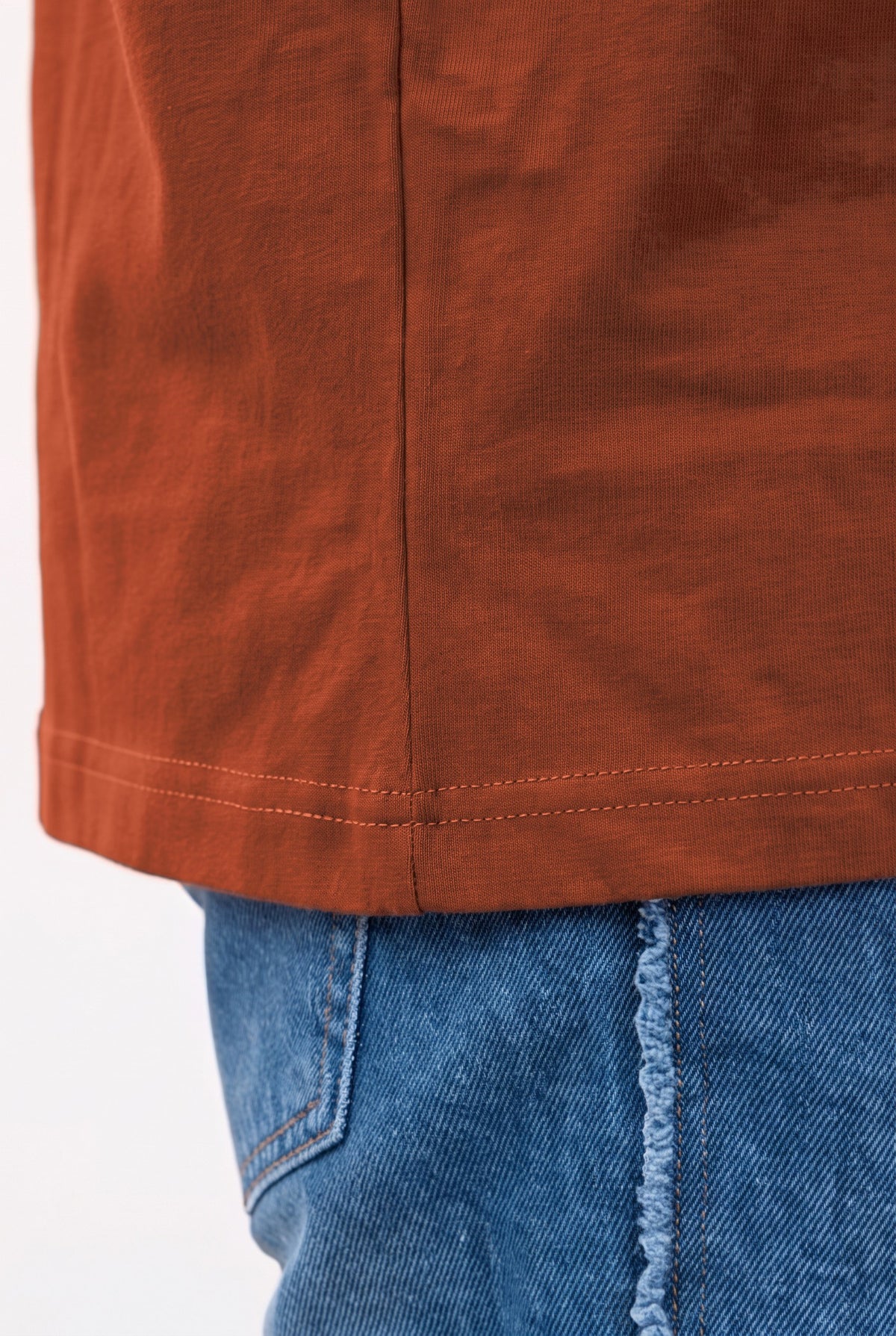 Close-up of the side seam and double-stitched hem on the brown tee